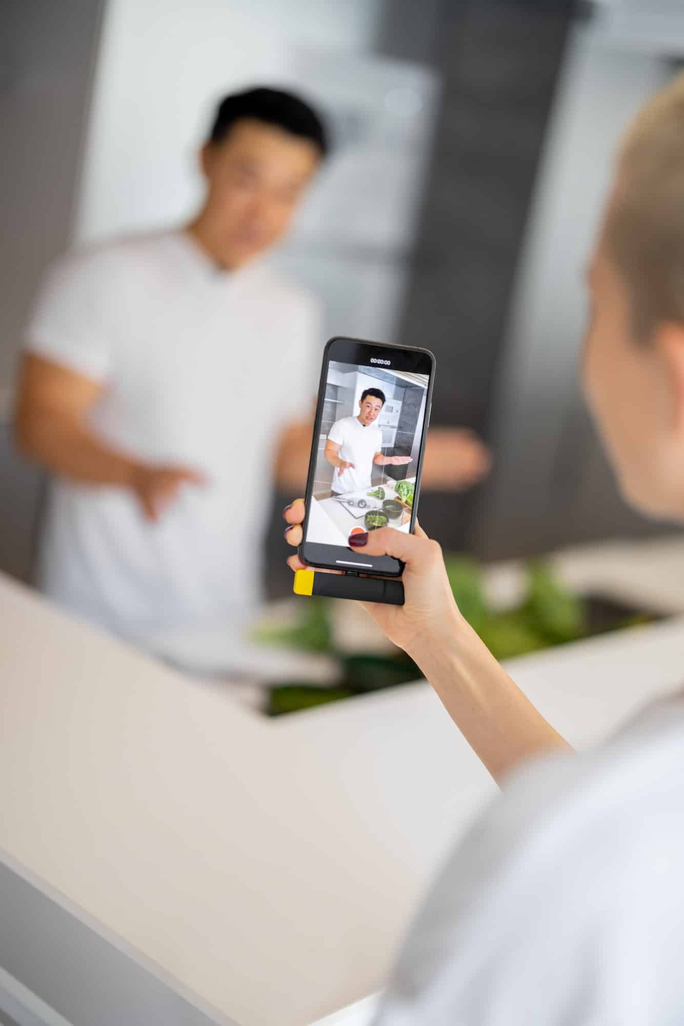 Woman take video on smartphone of man cook salad
